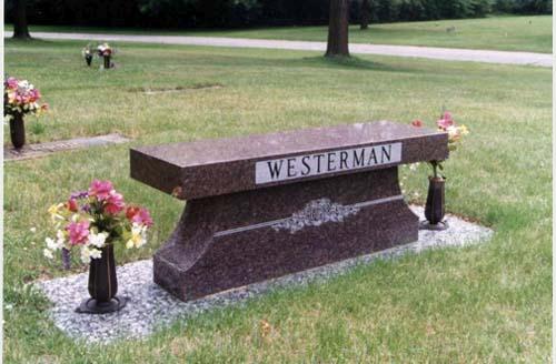 Memorial bench with engraved name and flowers, and two vases