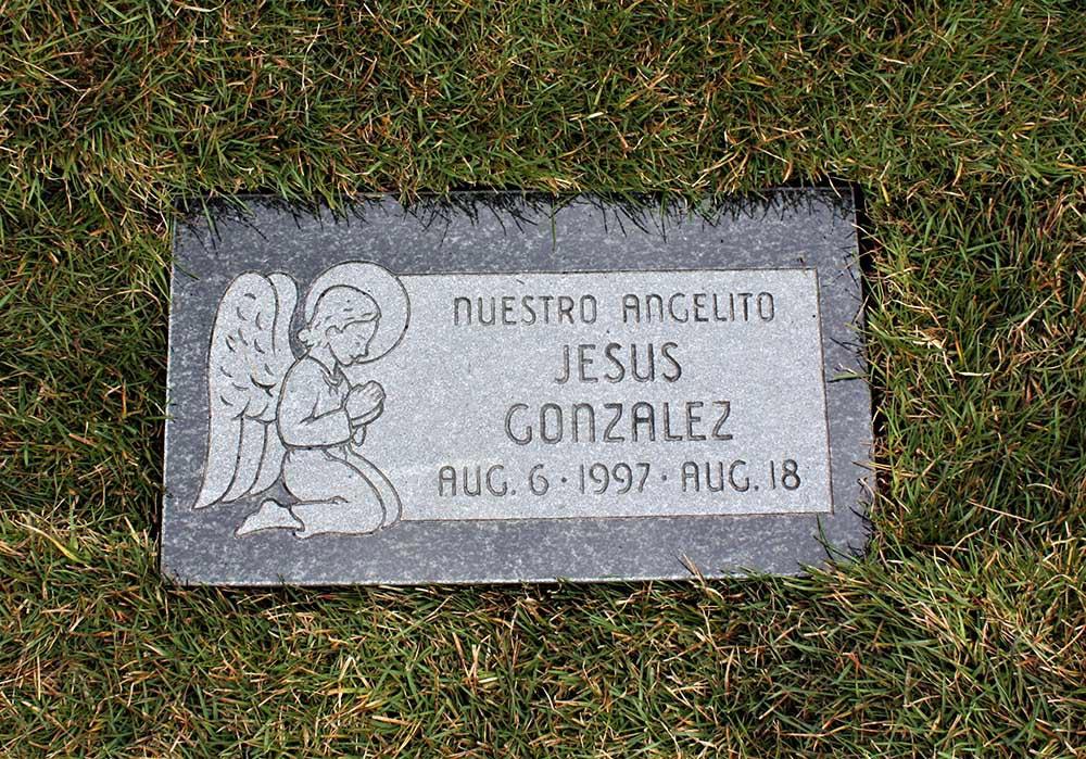 Child's marker with angel carving and Spanish lettering