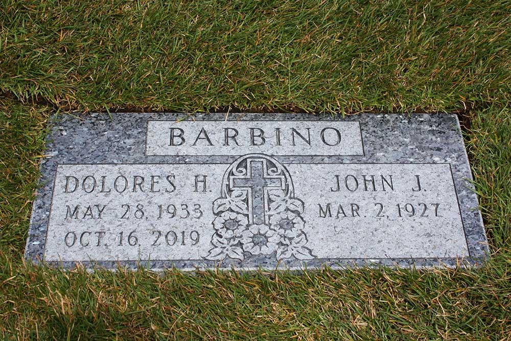 Blue granite marker with cross, flowers, and 2 names