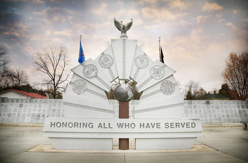 Tomah Veterans Memorial with inscription, centered globe, and eagle sculpture on top