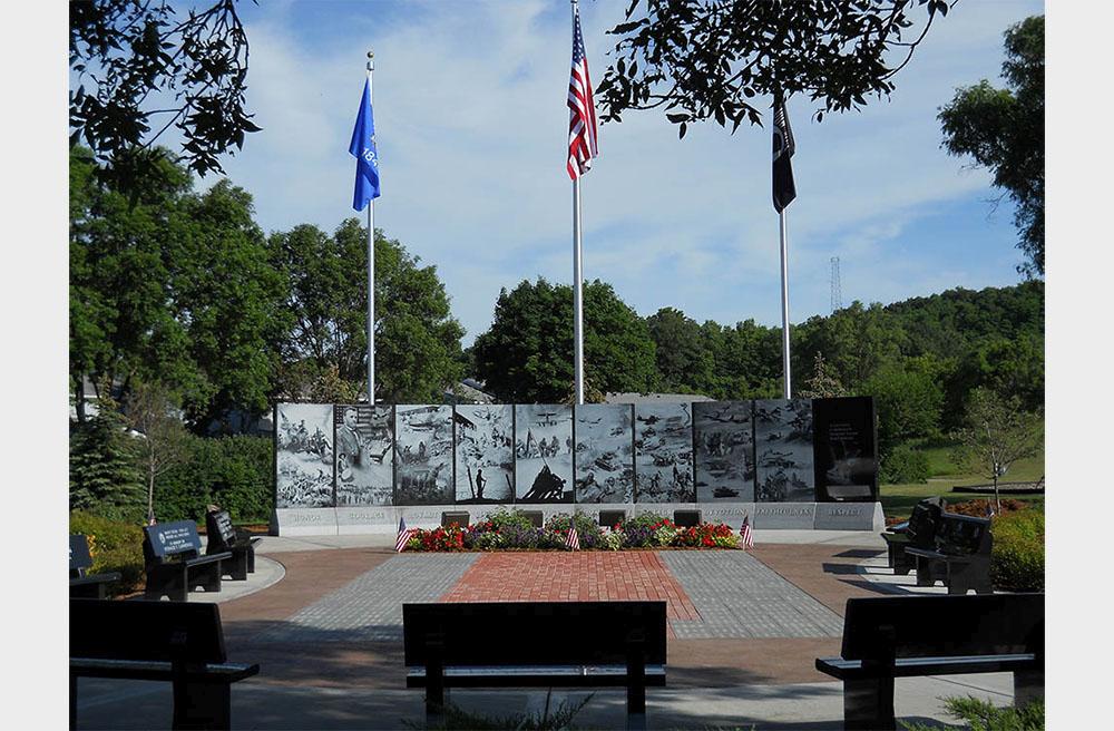 Far view of upright monuments with printed war imagery at Reedsburg Veterans Memorial