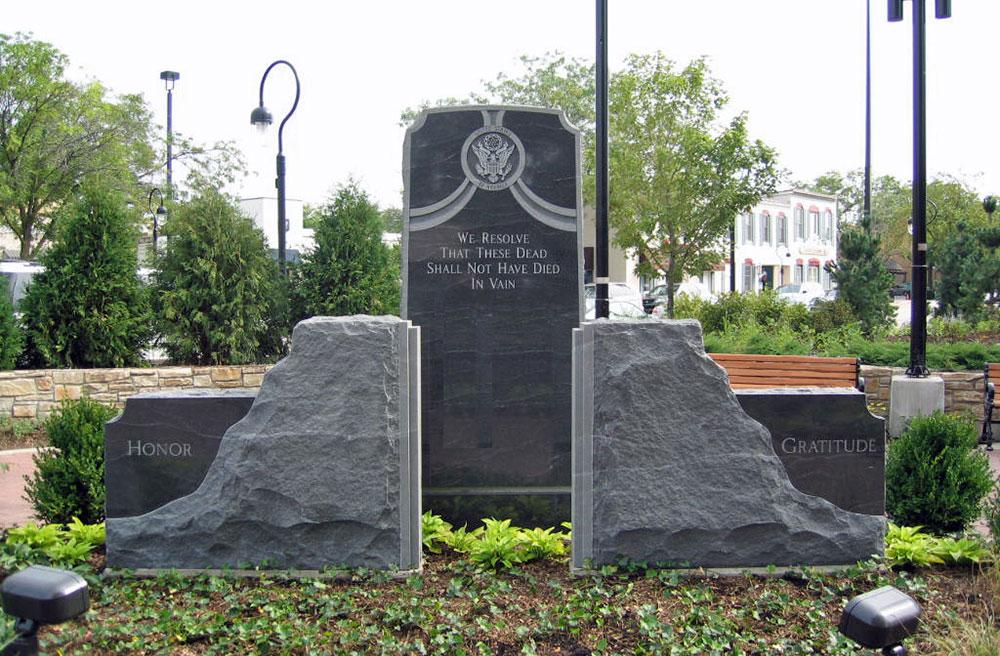 Upright monument and two stone slabs at naperville veterans memorial river walk