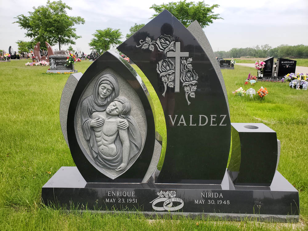 Family monument with images of Mary and Jesus, roses, and wedding rings