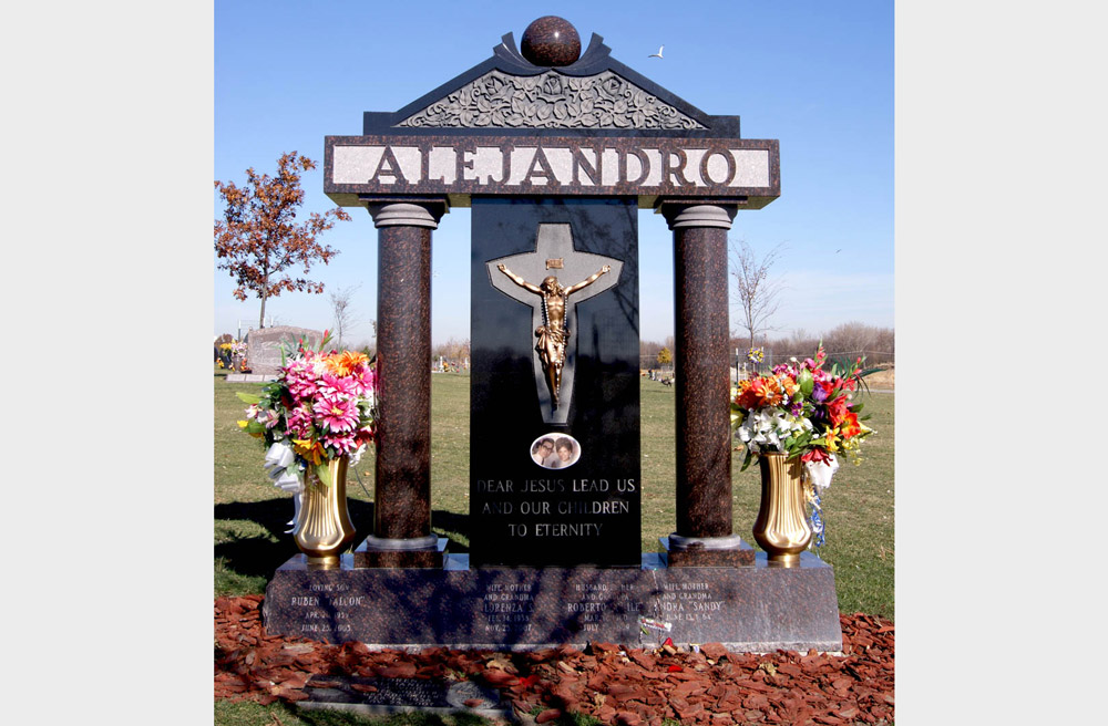 Family monument in multiple colors of granite with bronze Jesus, vases, carved roses, and a ceramic photo